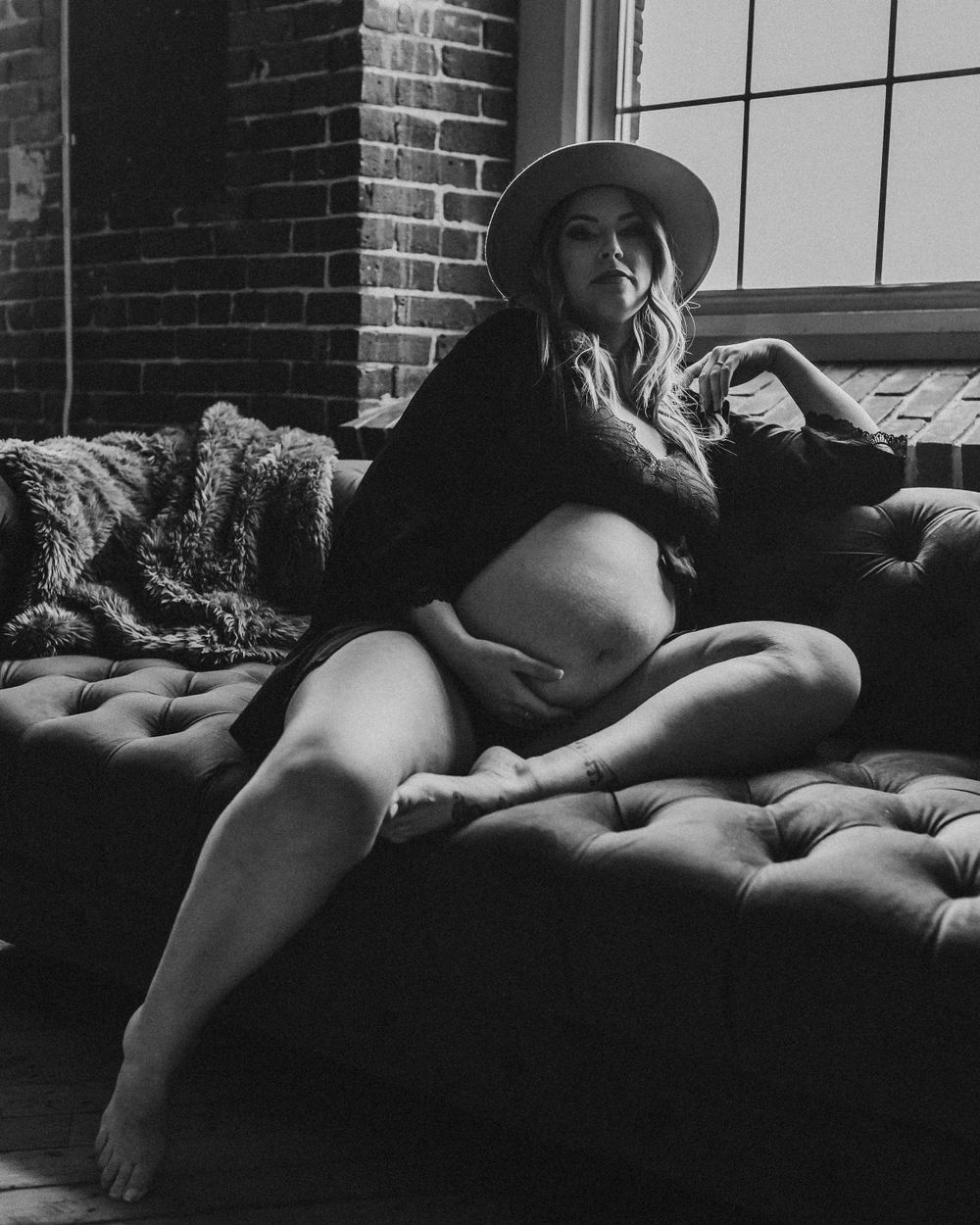 Black and white maternity photo showing silhouette on vintage tufted couch.