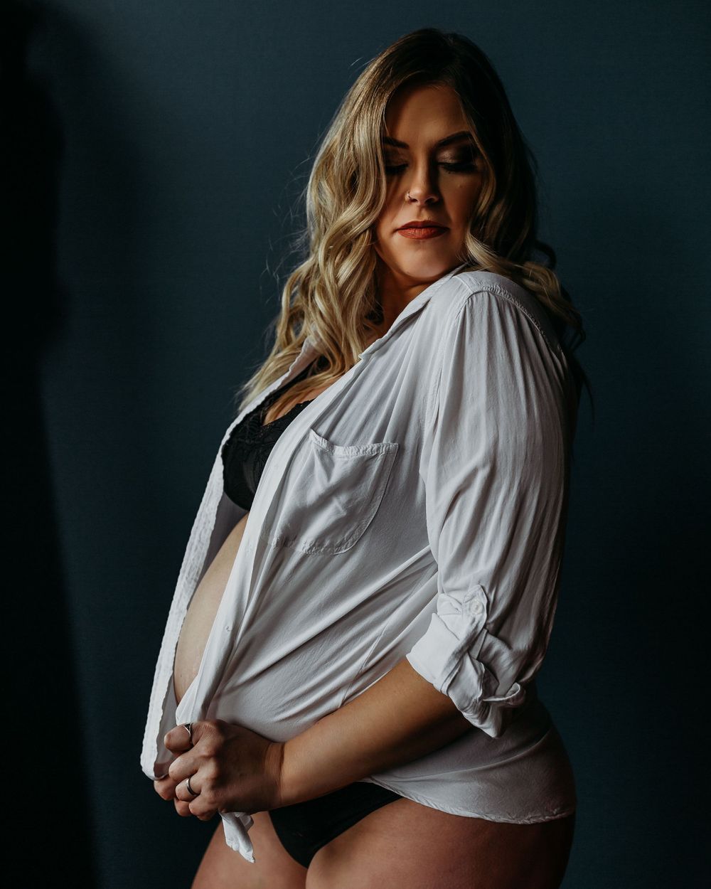 Artistic portrait in white button down shirt against dark background.