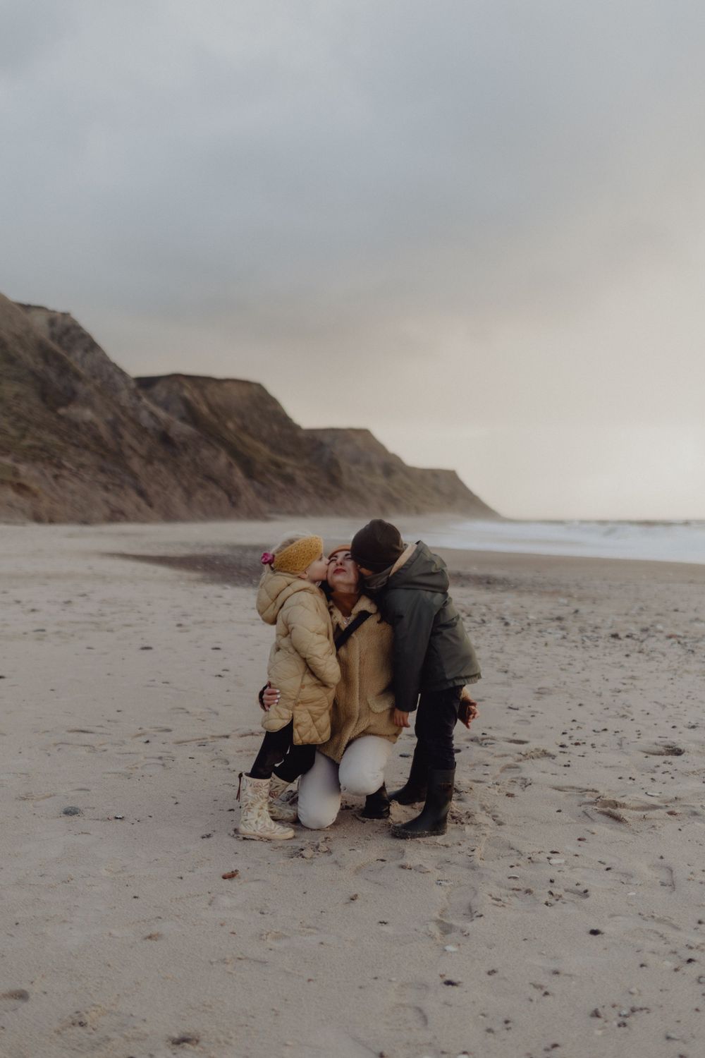 Intimate moment shared on a misty beach with cliffs in the background.