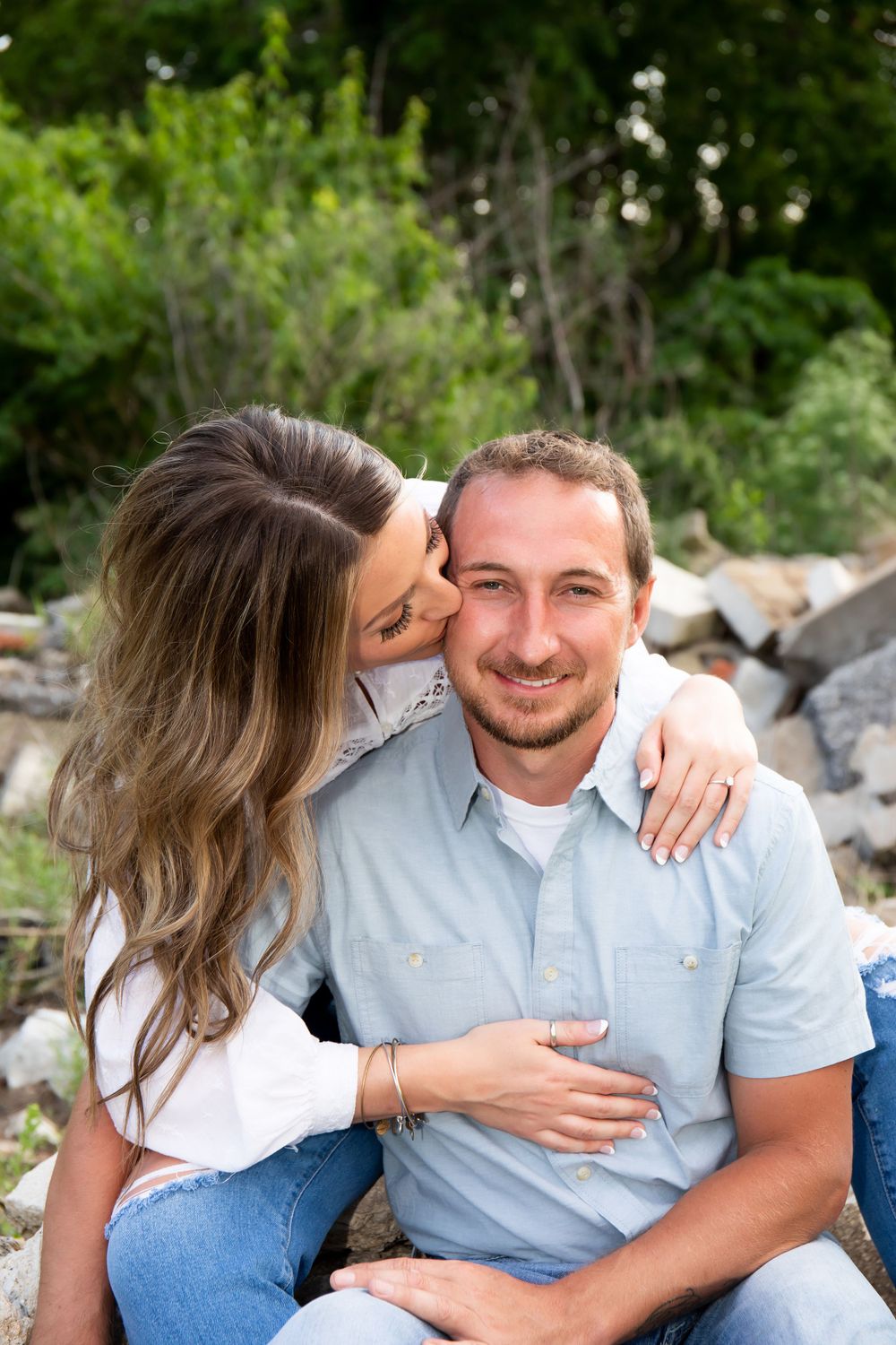 A romantic outdoor portrait of a couple sharing an affectionate moment among rocky terrain.