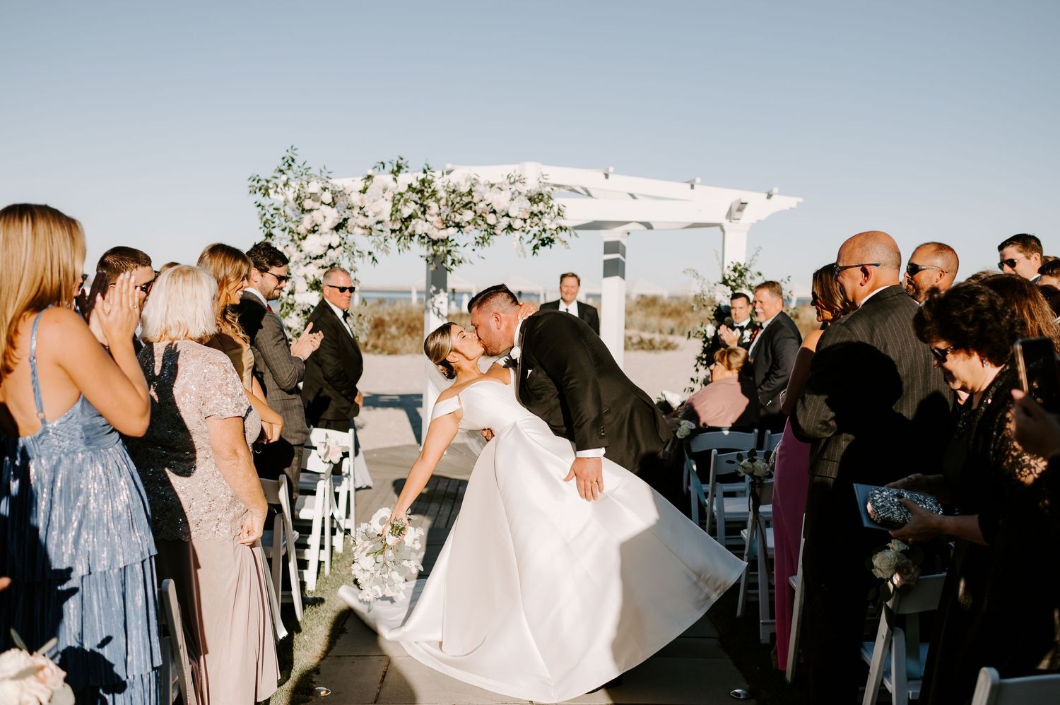 Wedding guests gather outdoors to celebrate during a sunset ceremony.