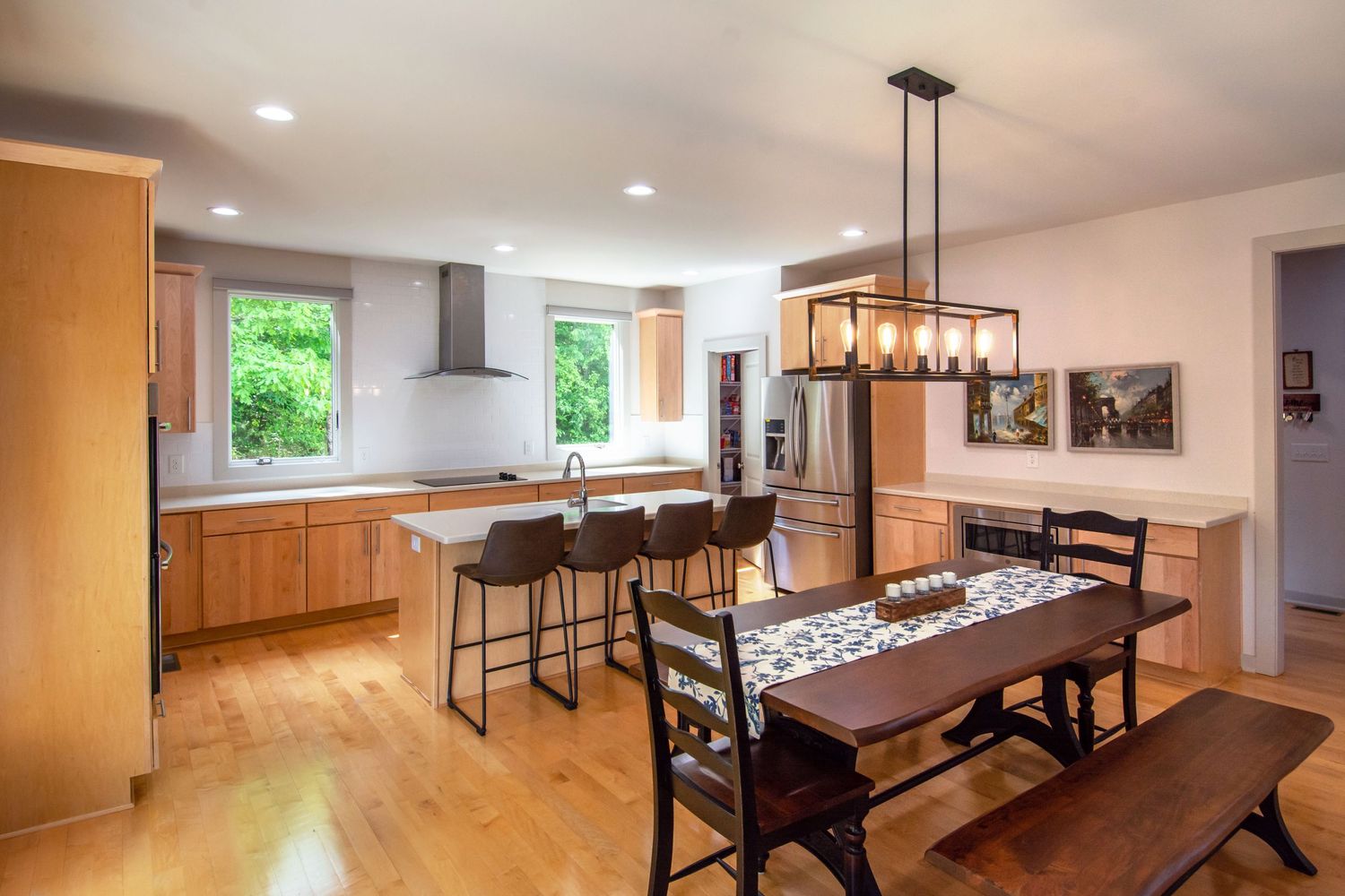 Modern open concept kitchen and dining area with wood cabinets and pendant lighting.
