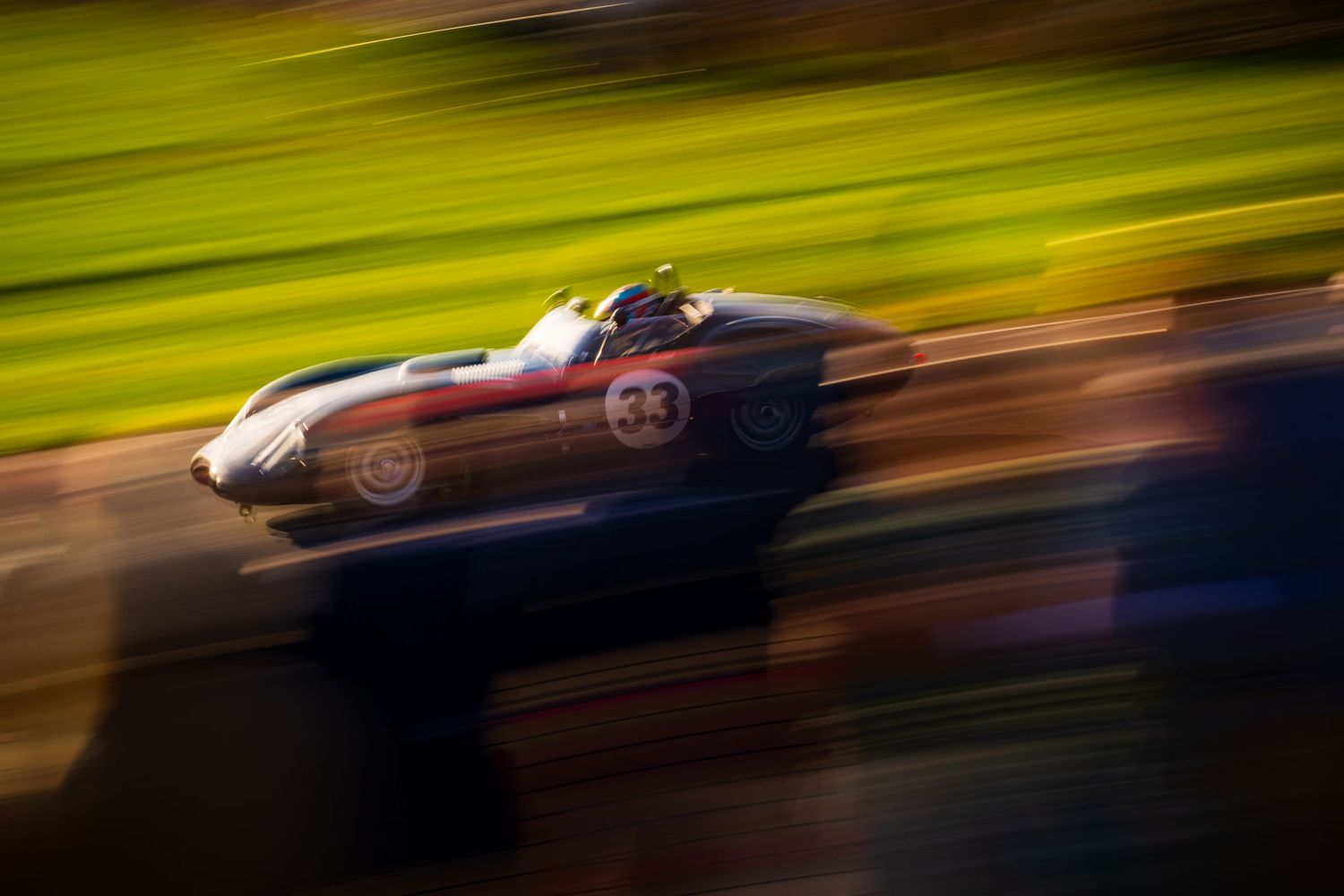 Motion-blurred racing cars speed past on a racetrack with vibrant green background.