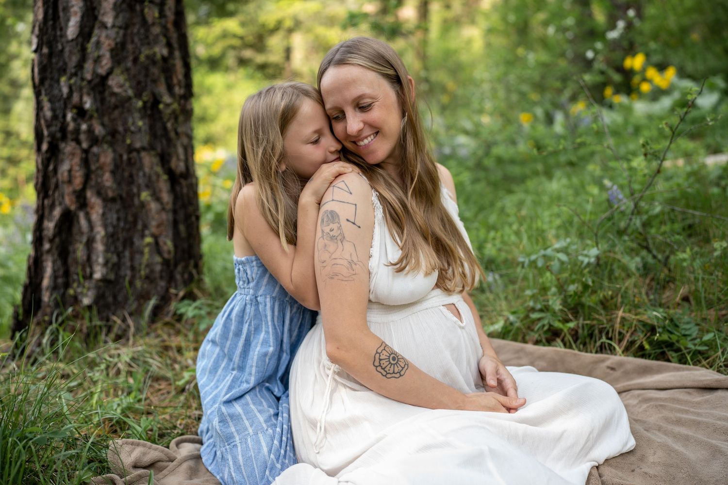 Two people embracing on blanket in forest surrounded by yellow wildflowers.