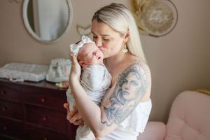 A tender moment captured as a parent holds and kisses their newborn baby in a cozy nursery.
