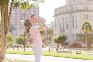 Joyful outdoor moment with baby being lifted in front of a historic building.