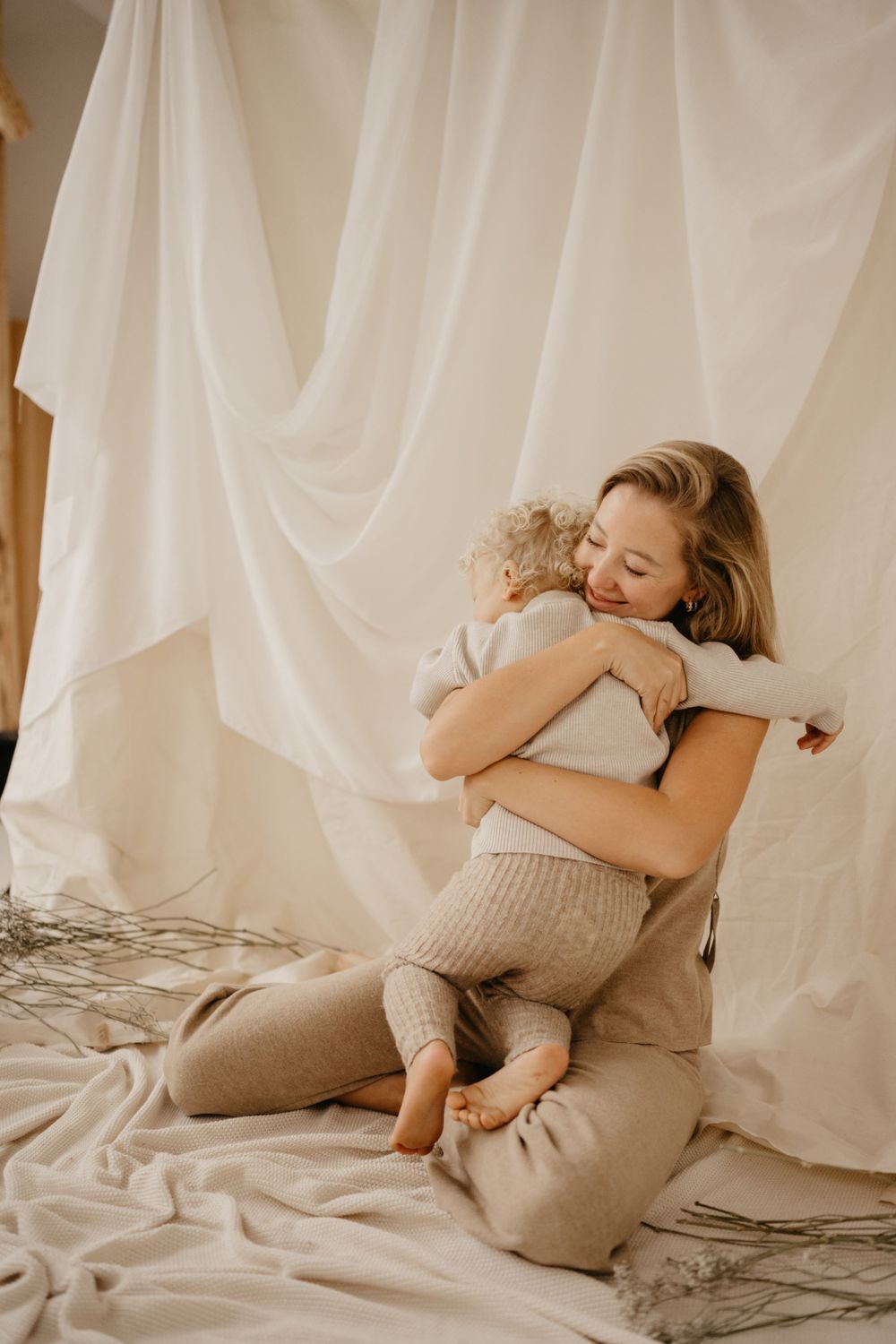 Intimate moment of parent and child hugging on white fabric backdrop.