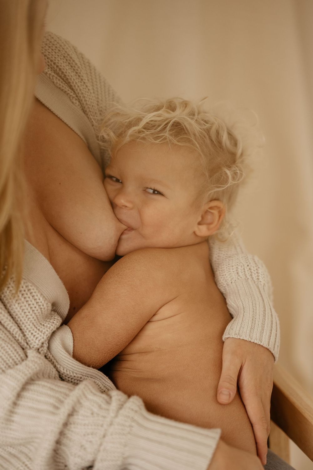 Intimate nursing moment with baby in soft natural light.