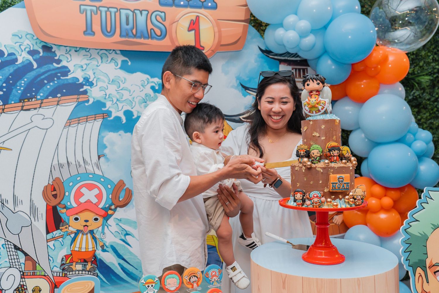A nautical themed party setup with blue and orange balloon decorations and dessert display.