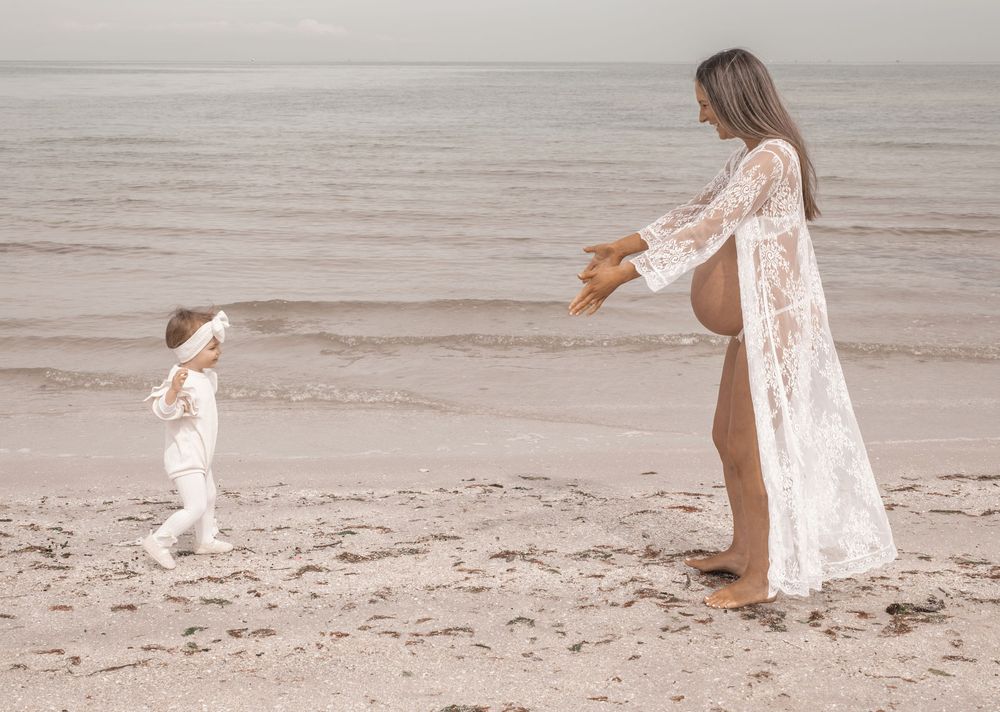 A series of dreamy black and white beach photos showing a person in a flowing white dress walking along the shoreline.