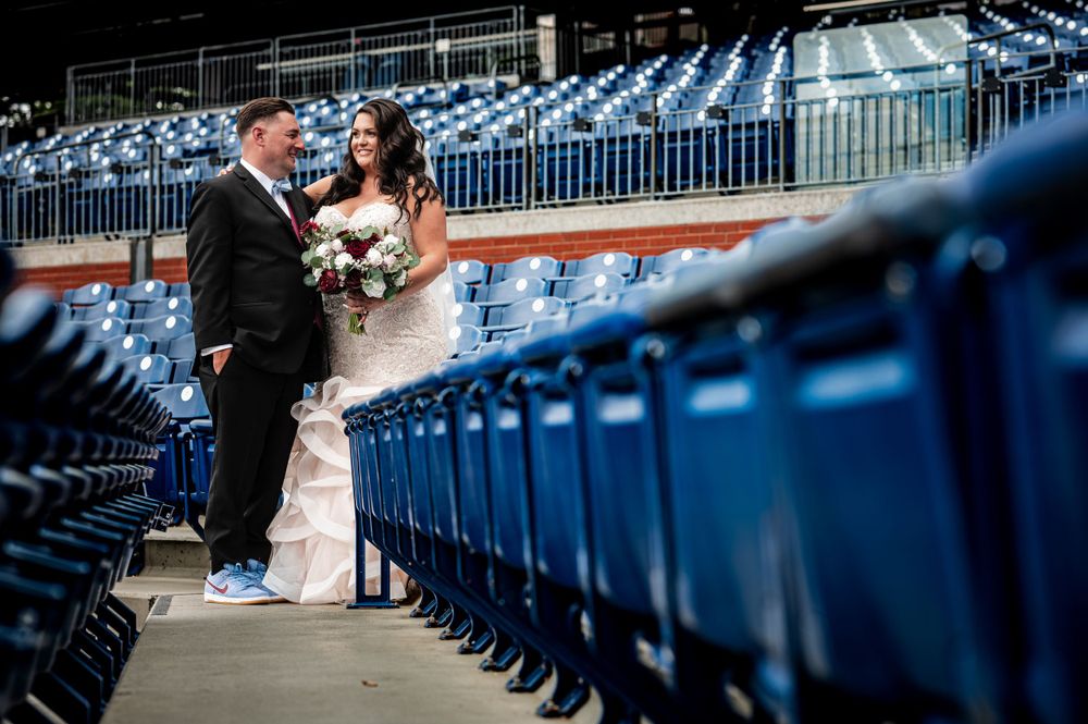 Wedding couple posing among blue stadium seats at Citizens Bank Park.