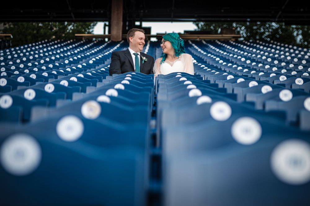 Wedding portrait between rows of blue stadium seats at Citizens Bank Park.