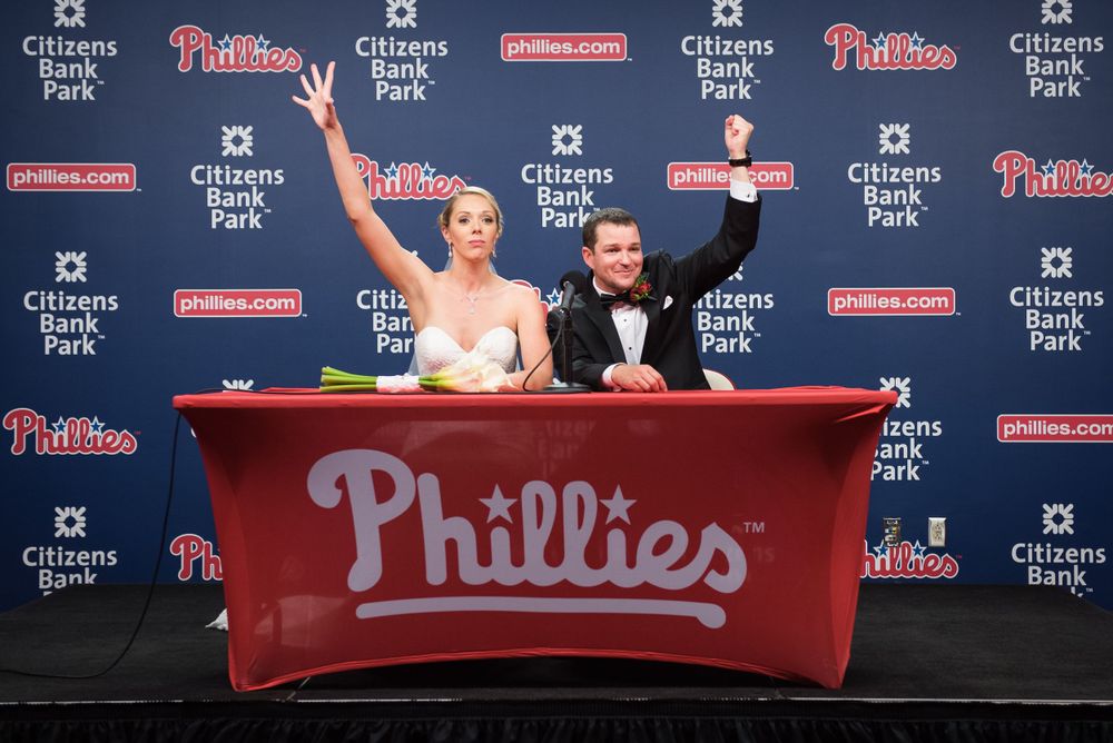Celebratory pose at Phillies press conference backdrop in Citizens Bank Park.