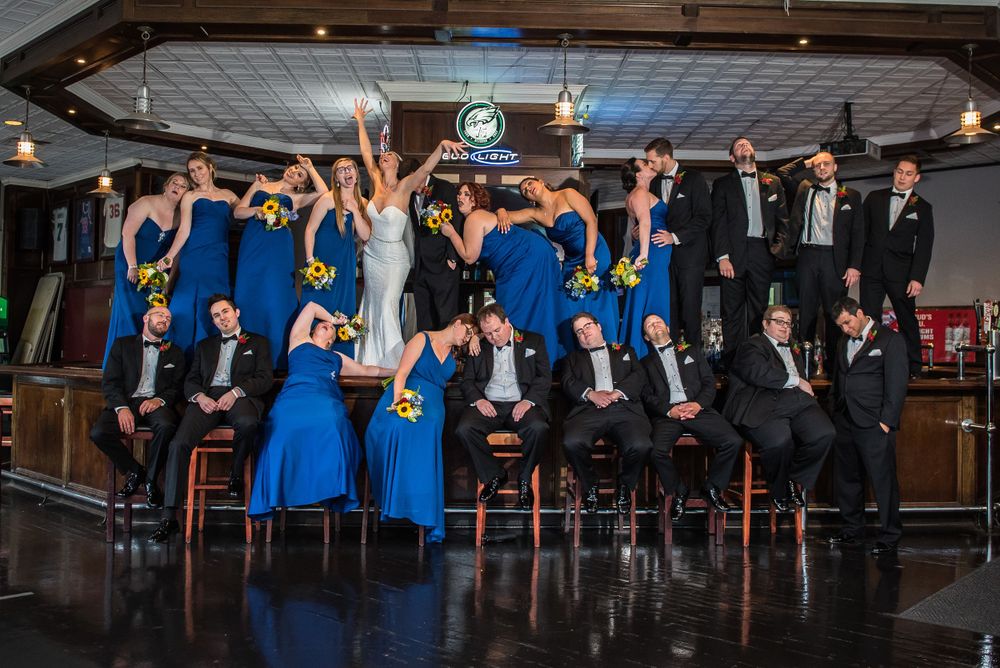 Wedding party posing dramatically with bridesmaids in blue dresses and groomsmen in dark suits in Citizens Bank Park.