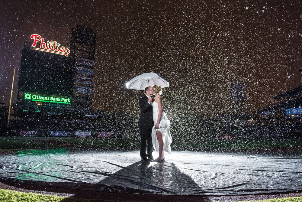 Dramatic nighttime pose in the rain at Citizens Bank Park with Phillies sign glowing.