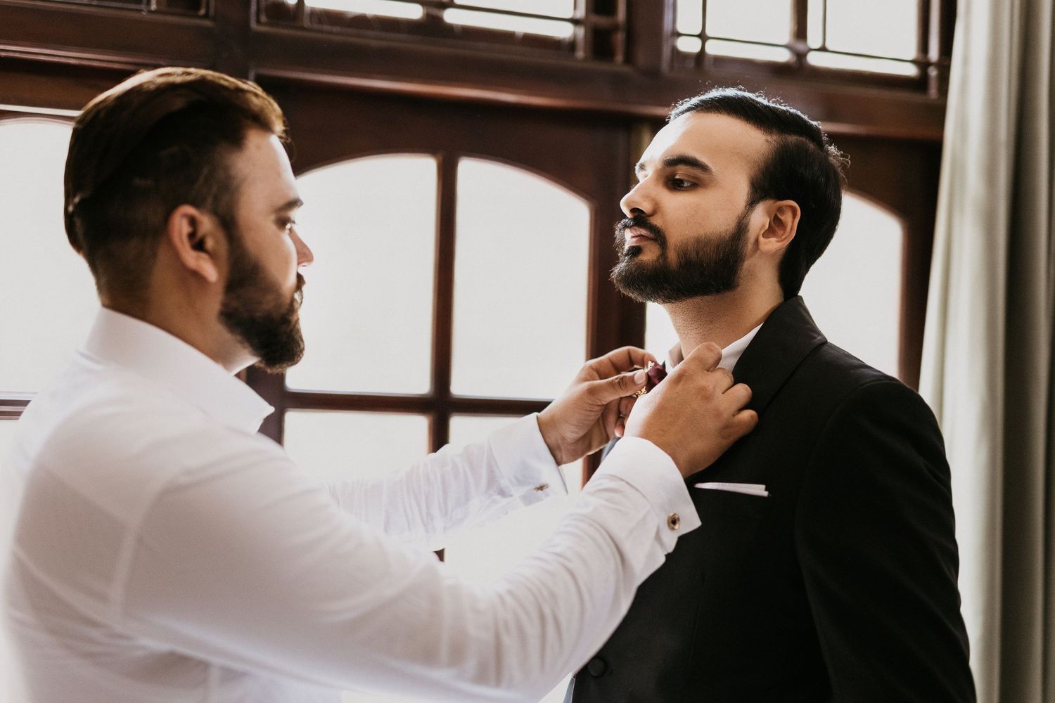 A formal dressing scene shows final adjustments being made to neckwear.