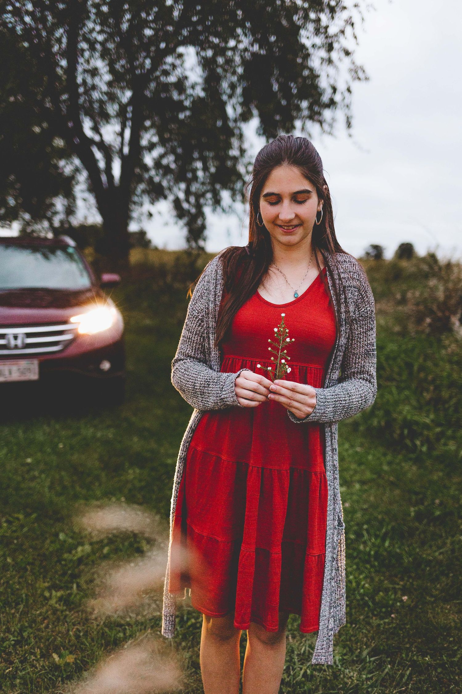 senior girl photoshoot with her car she drives in background and holding a flower located hartland wi