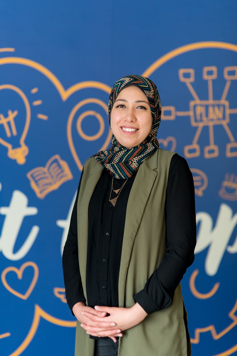 Professional portrait against blue wall with creative illustrations and icons.