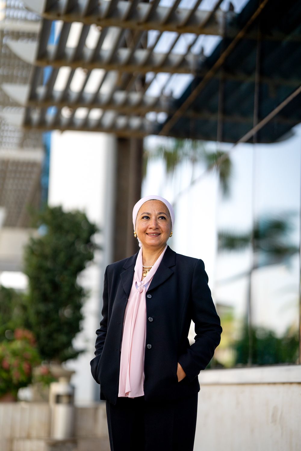 Professional outdoor portrait under architectural pergola with palm trees.