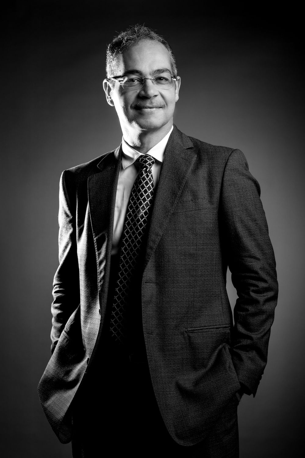 Black and white corporate portrait of person in business suit and tie with confident pose.