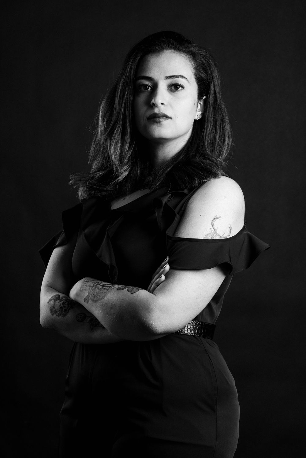 Black and white studio portrait featuring dramatic lighting and off-shoulder dress styling against dark background.
