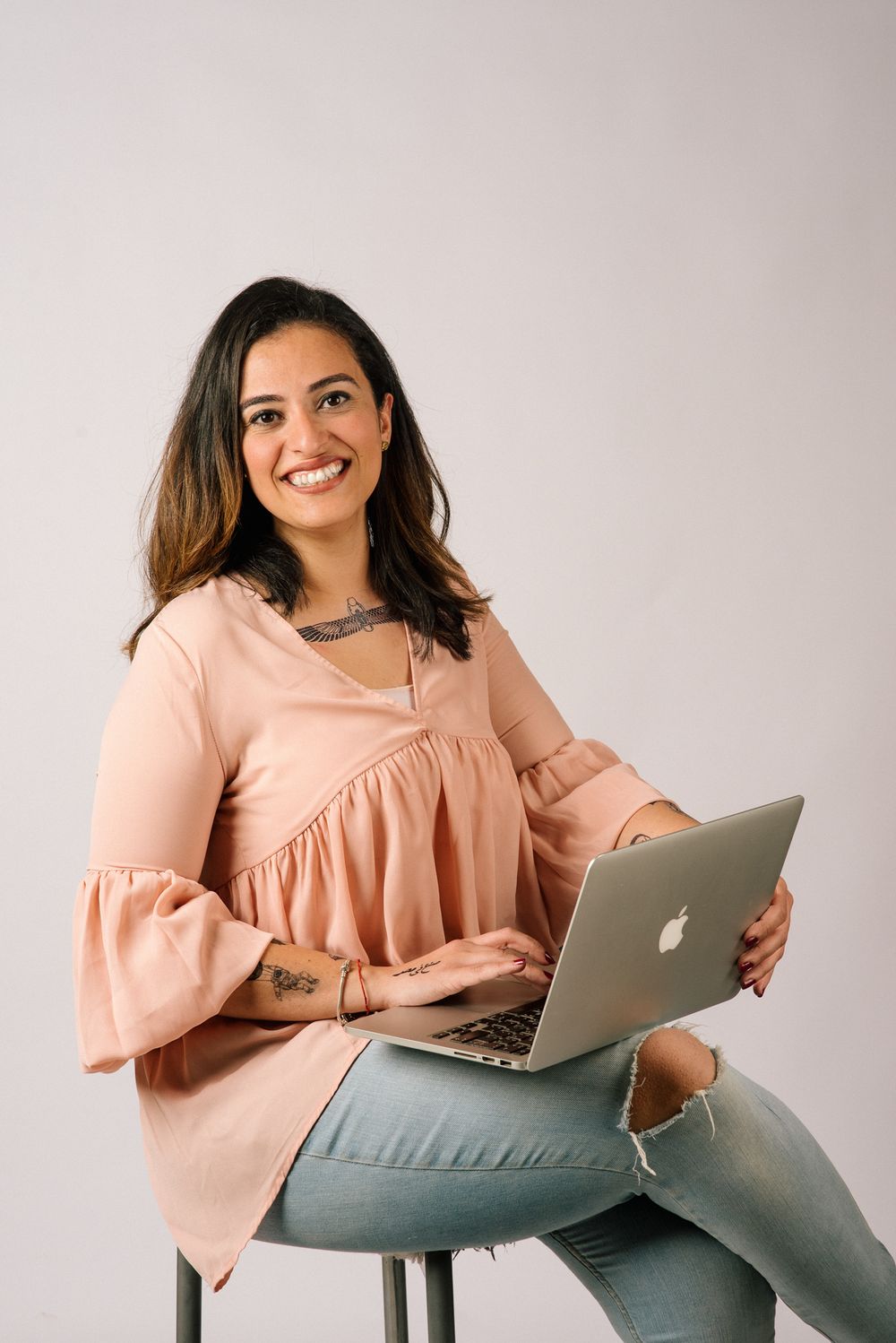 Casual professional working on laptop wearing peach-colored blouse.
