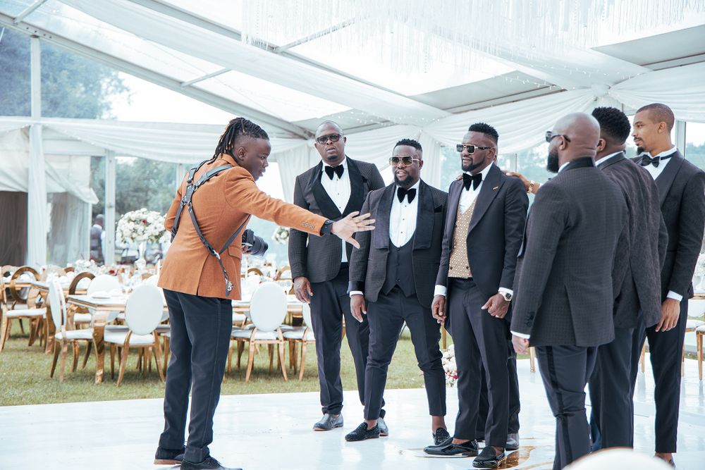 Wedding photographer directing group shot in elegant tent venue.