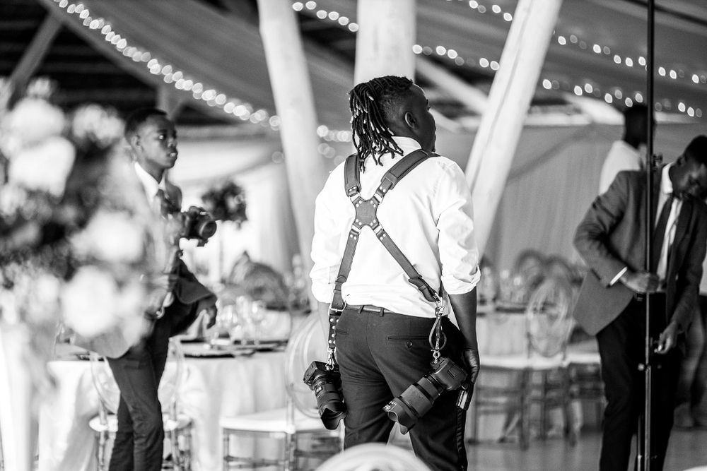 Black and white photo of a wedding reception dance floor with elegant indoor decor and string lights overhead.