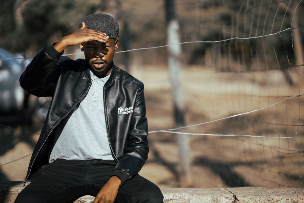 Photographer in leather jacket sitting outdoors during golden hour photo session.
