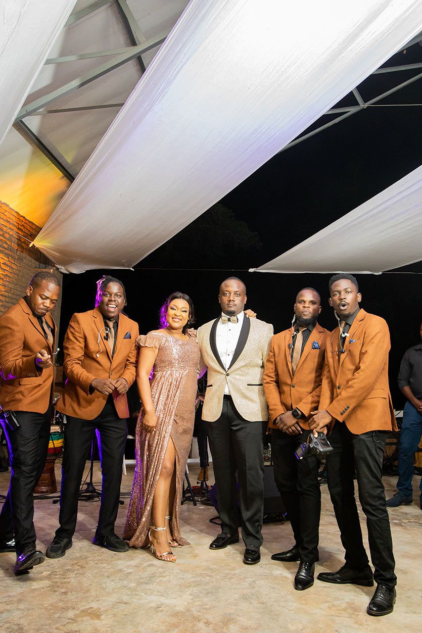Wedding photography team in coordinated brown suits posing at an evening reception.