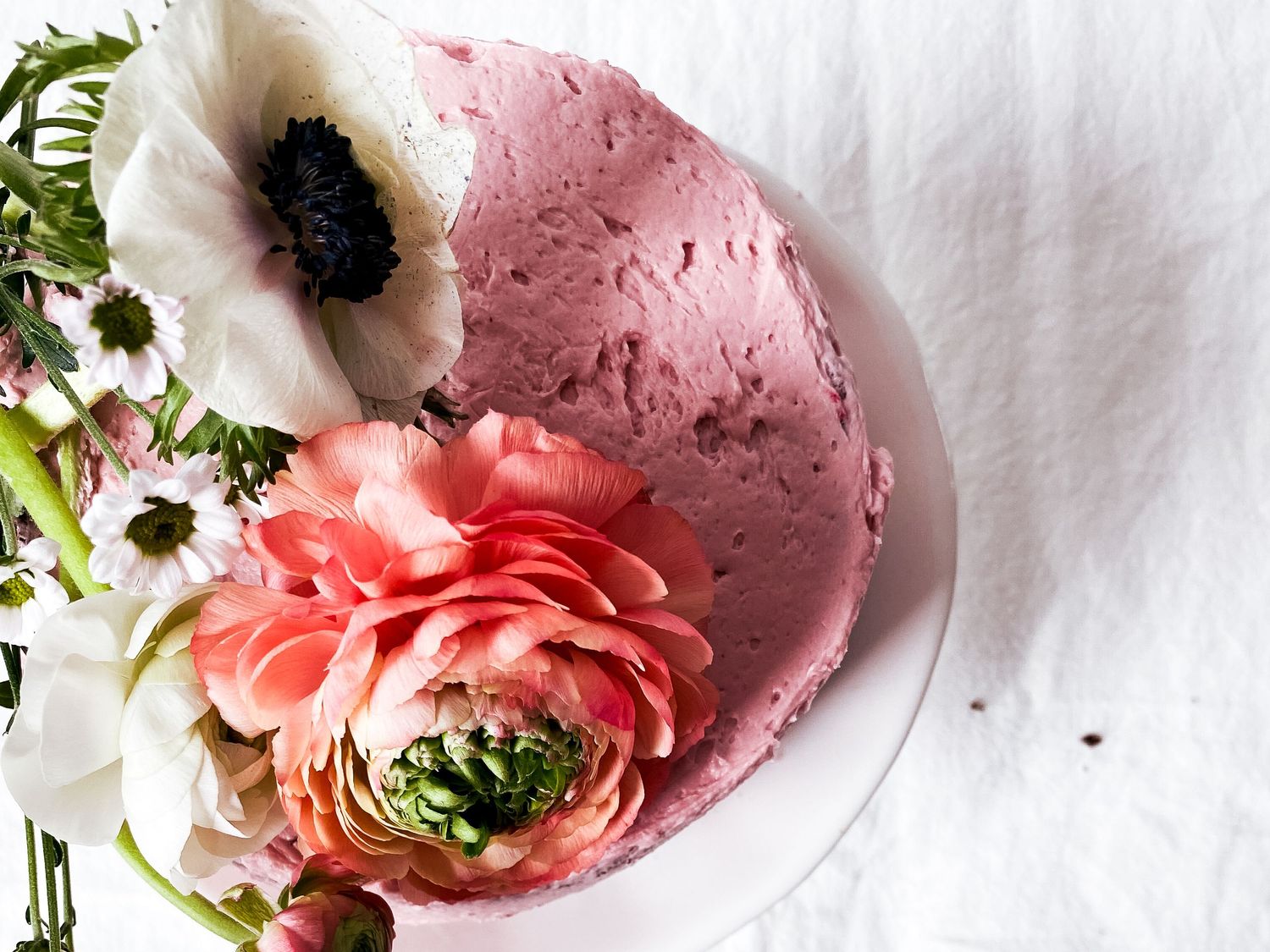 Pink ice cream scoop with white anemone and coral ranunculus flowers on white background.