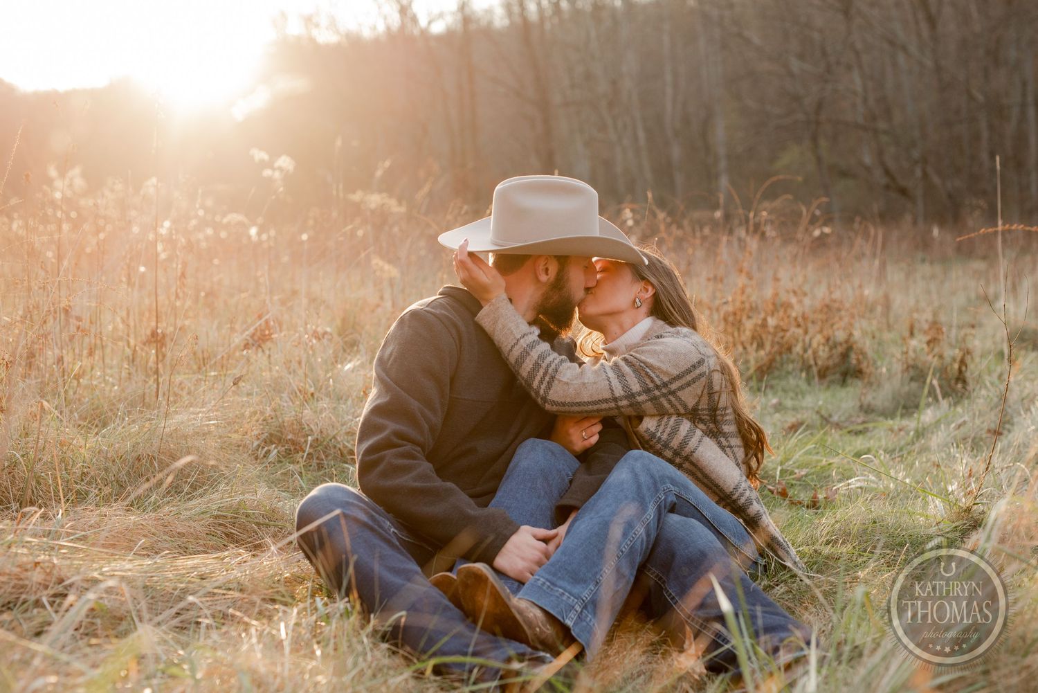 A tender moment captured between a couple sitting in a sunlit autumn field.