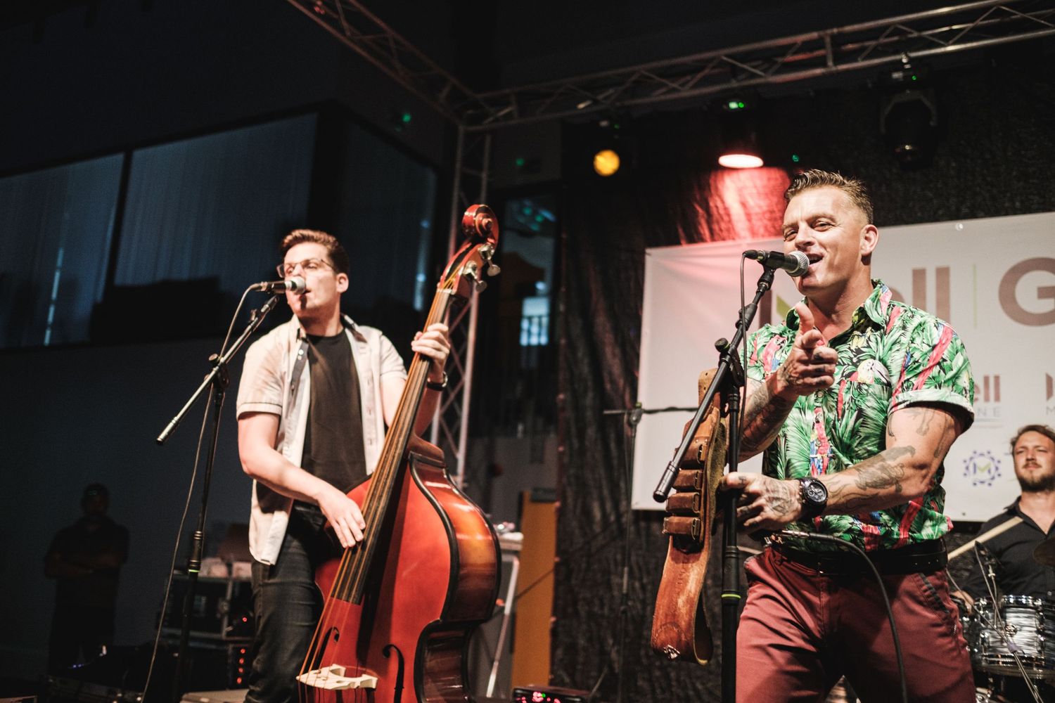 Musicians performing on stage with instruments at live concert venue.