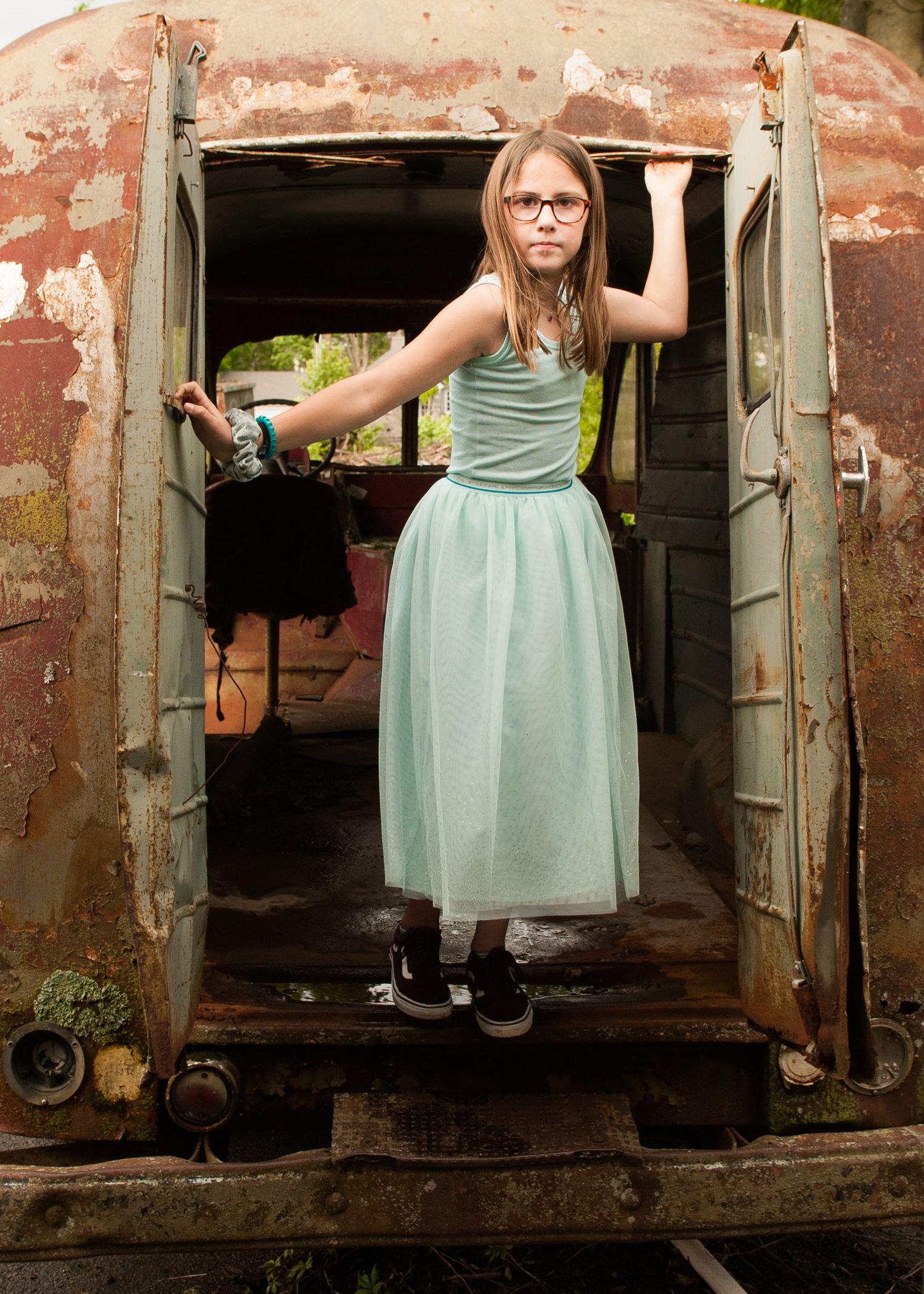 Figure in mint green dress poses in rustic train car doorway.