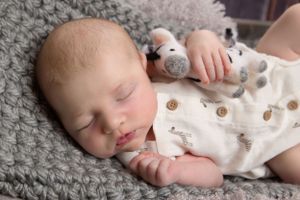 newborn baby in a zebra outfit holding a sebra