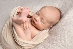 newborn baby wrapped in a cream wrap