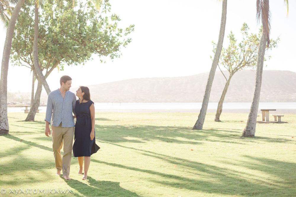 Couple walking hand in hand on grassy lawn with ocean view.