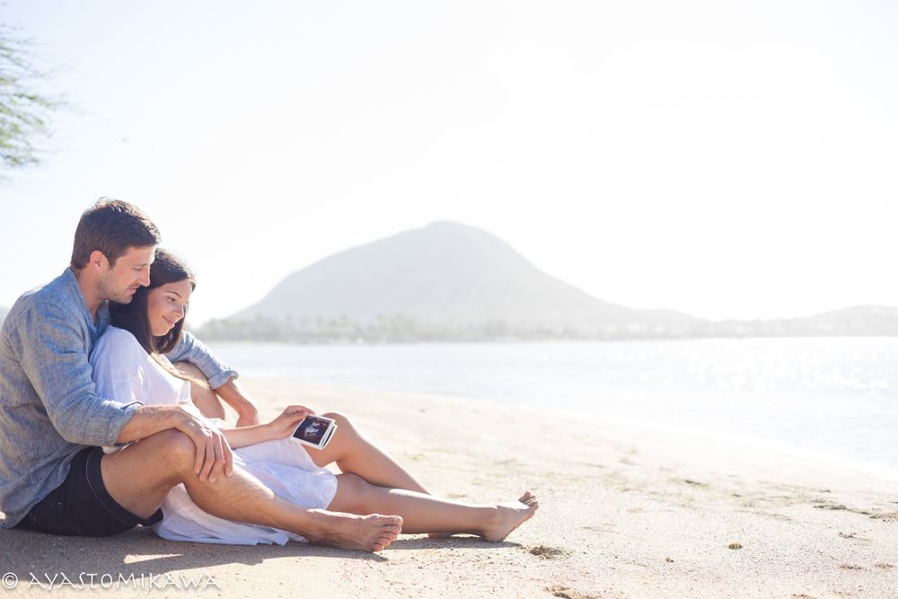 Couple relaxing on sandy beach with mountain view in background.
