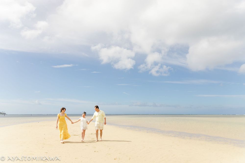 People walking together on empty white sand beach under bright blue sky.