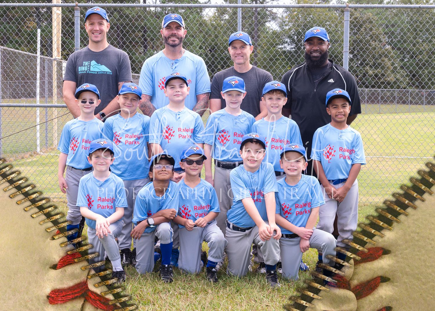 Youth baseball team posing for group photo with coaches on baseball diamond.