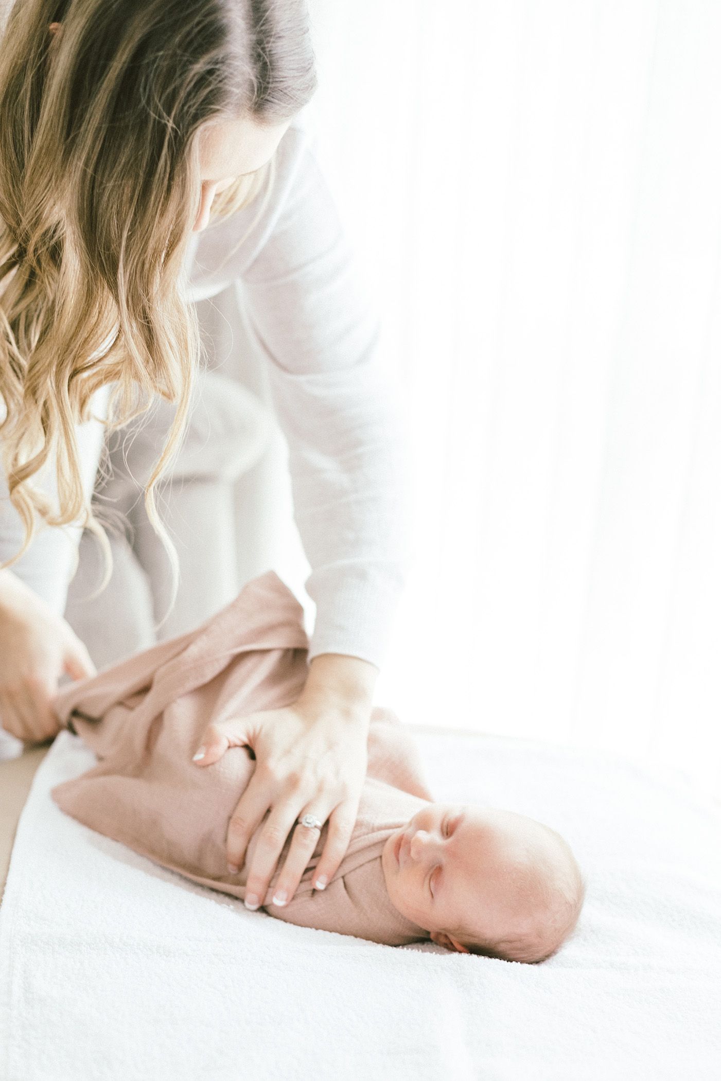 Series of intimate shots showing gentle interaction with sleeping newborn on white backdrop.