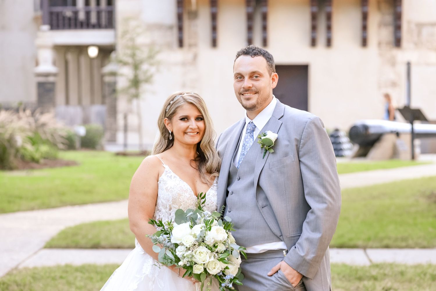 A wedding portrait outdoors featuring elegant white and green floral bouquet arrangements.