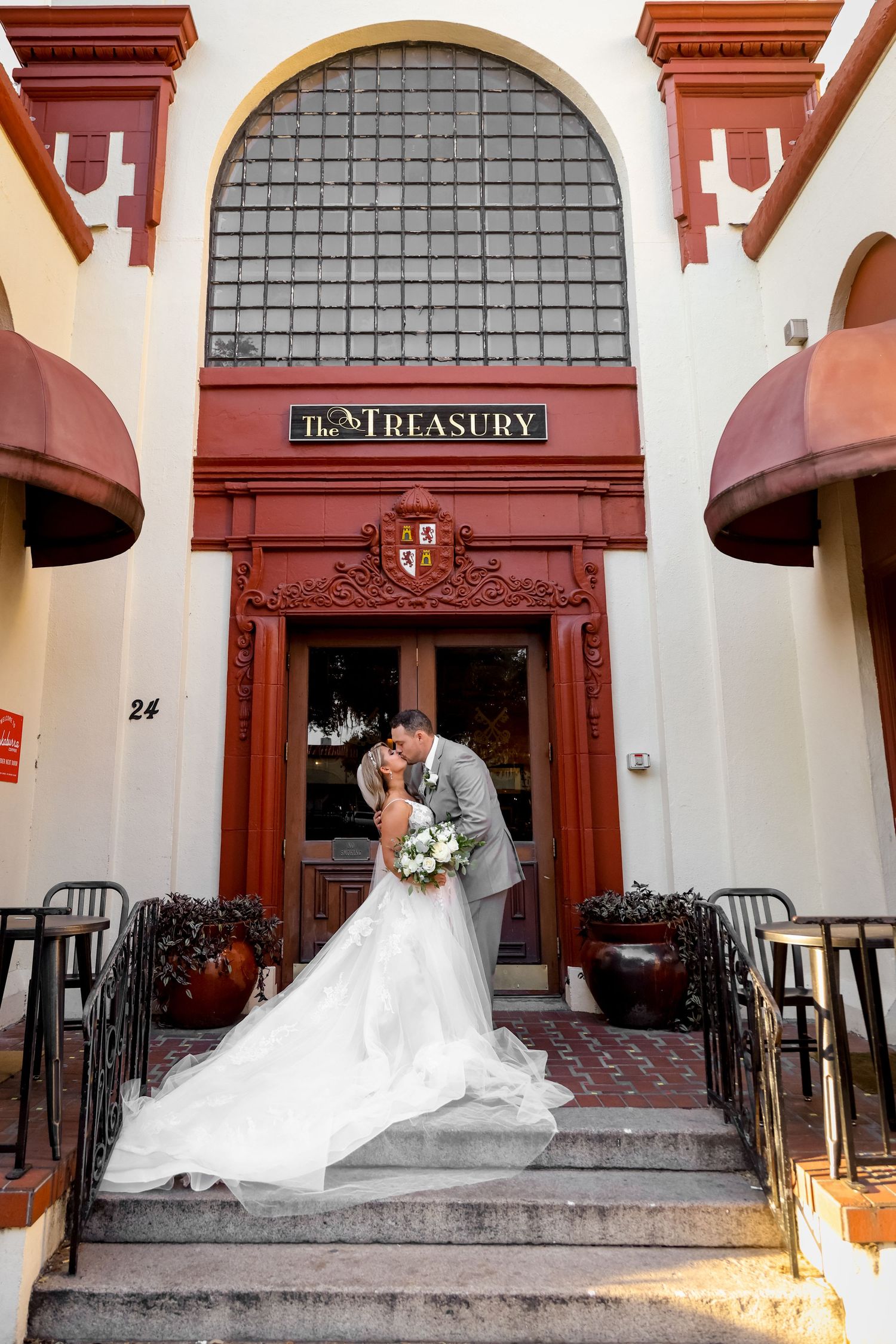 A couple sharing a romantic moment at The Treasury venue entrance with ornate architectural details.