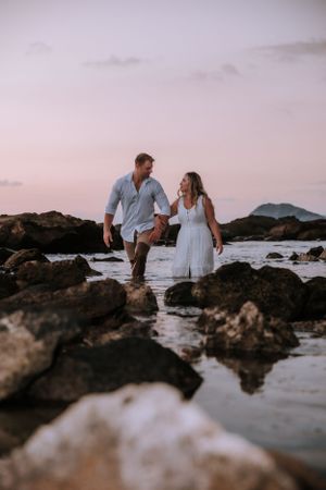 Couple explores rocky coastline together during sunset photoshoot.
