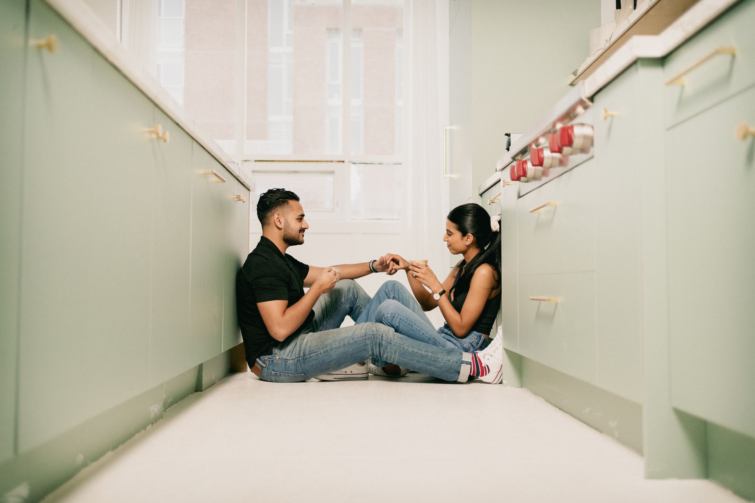 A couple sits together on stairs sharing an intimate moment in casual attire.