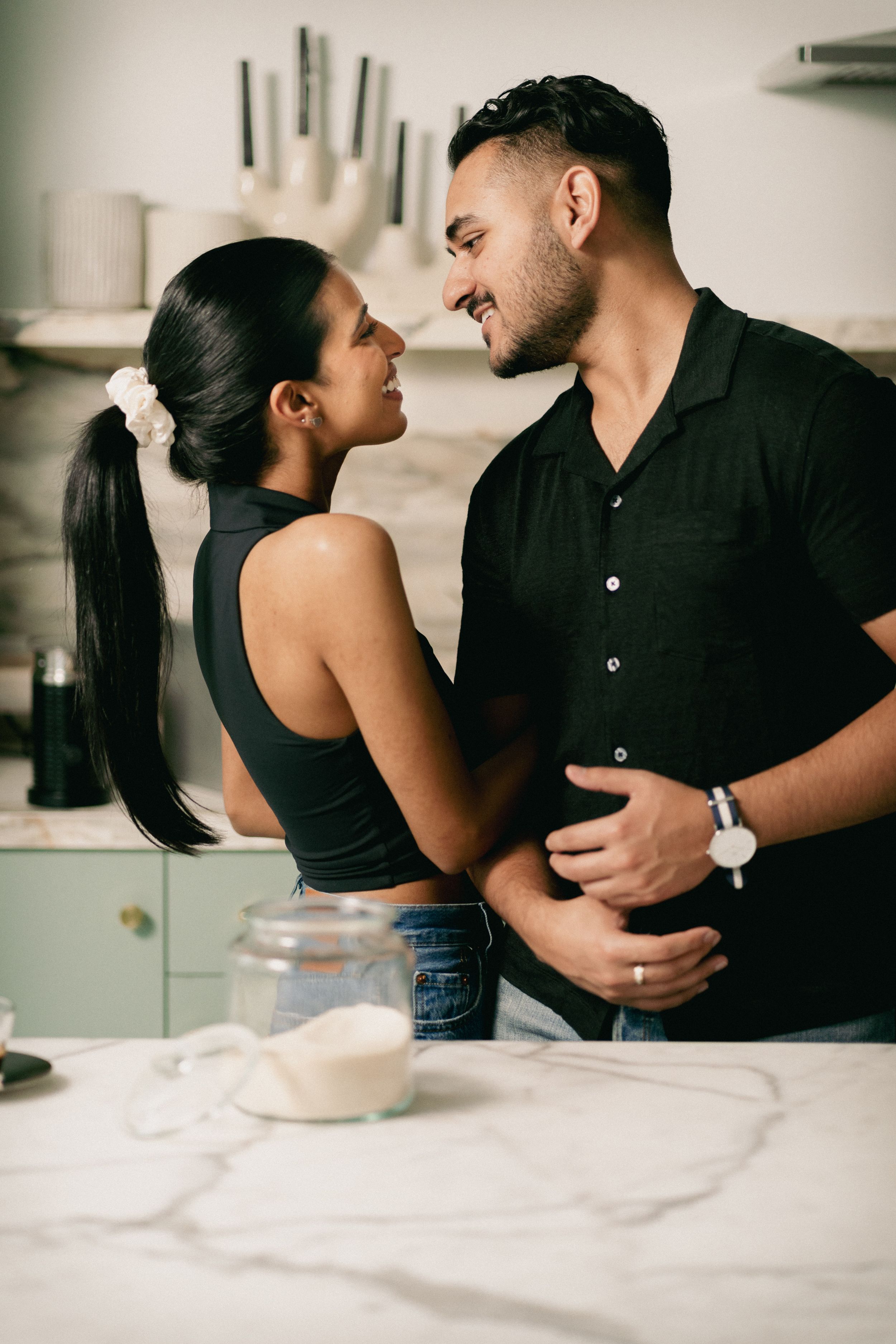 A couple shares an intimate moment while cooking in their stylish kitchen.