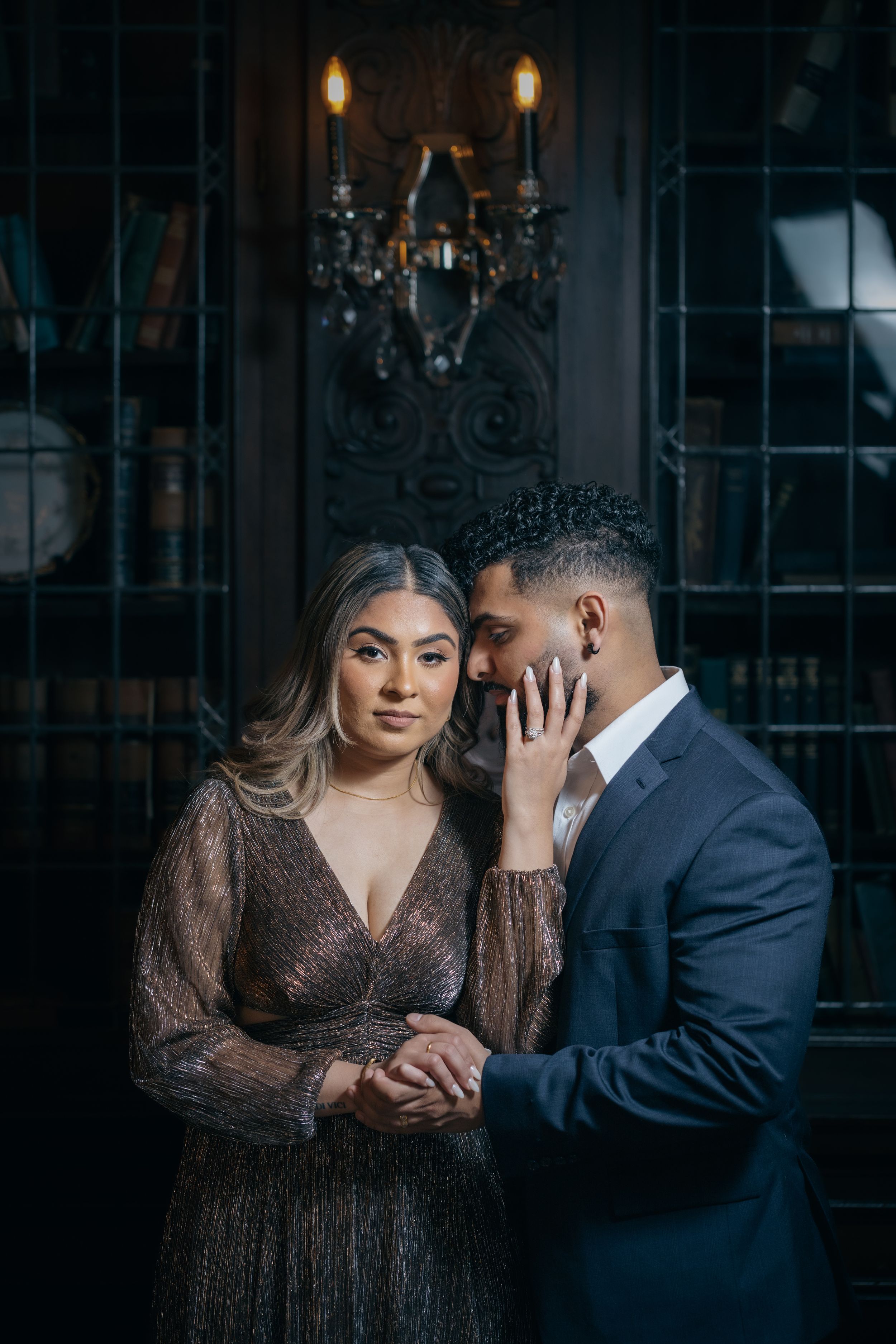 Romantic dimly lit indoor photoshoot with couple in elegant evening wear.