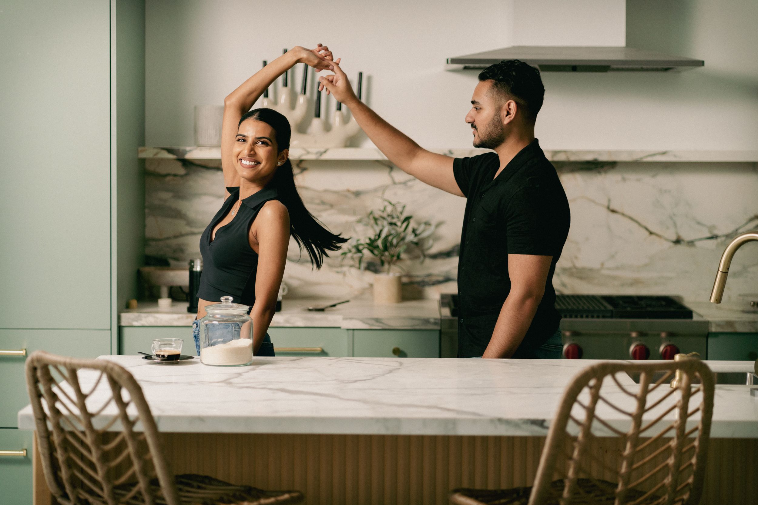 A playful couple dances while baking in their modern white kitchen.