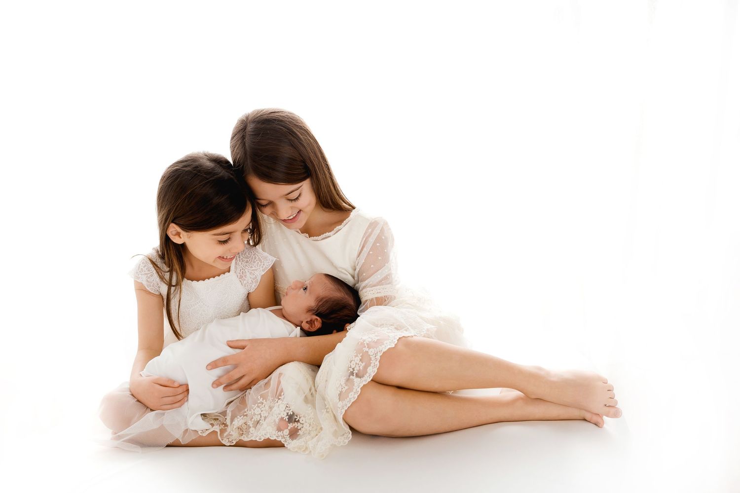 Tender family portrait with white dresses against pure white background.