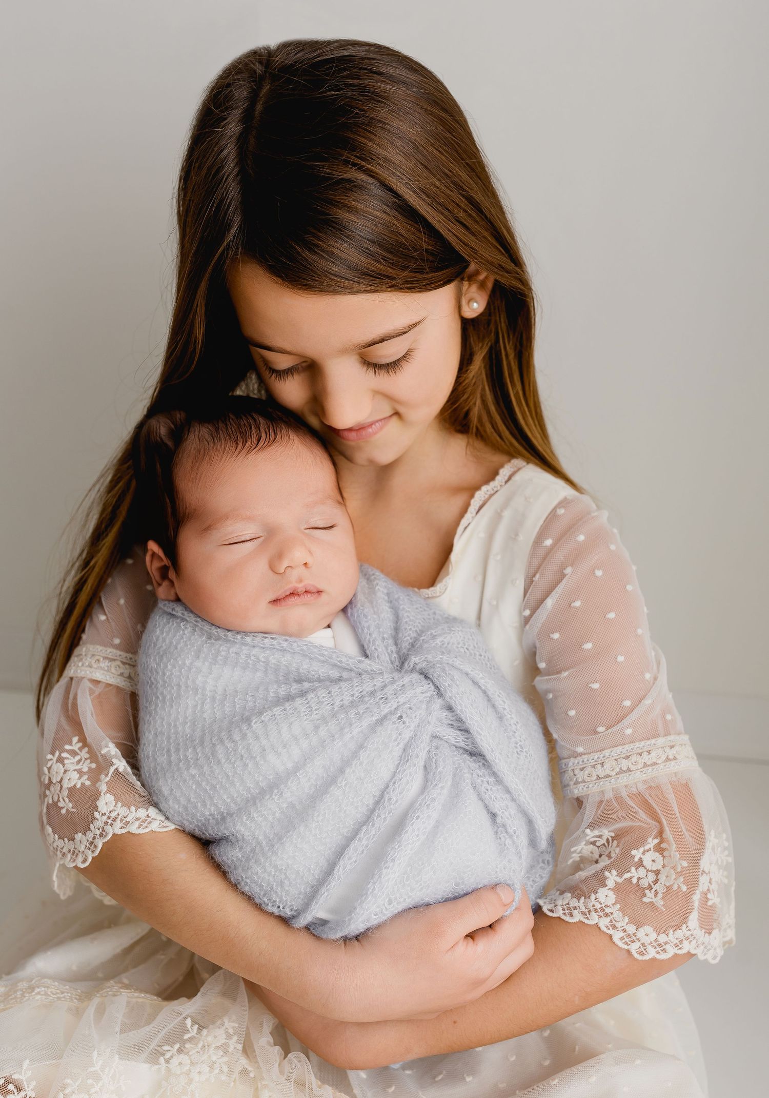 Intimate family moment captured in soft grey tones with delicate lace details.
